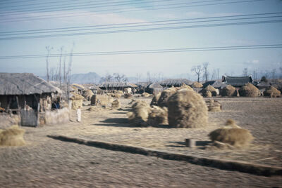 A farm house with many piles of hay